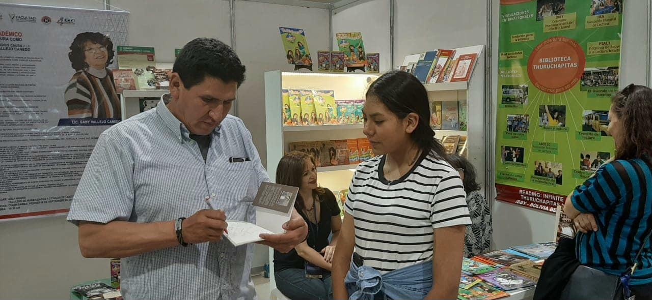 David Vildoso firmando libros para una joven lectora en la Feria del Libro