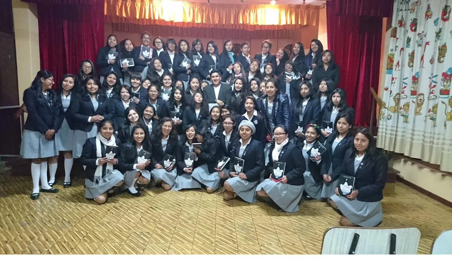 David Vildoso con alumnas de colegio sosteniendo sus libros en un evento literario